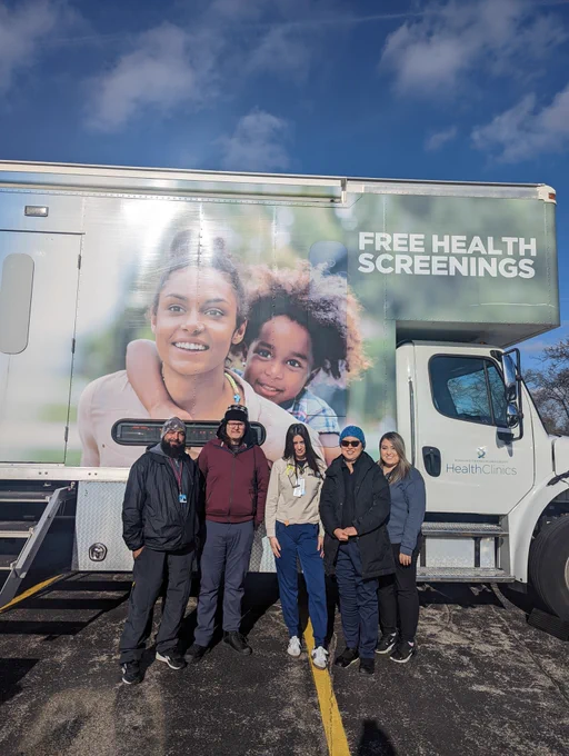 Five members from the Care Coach team stand in front of the vehicle to pose for their picture.