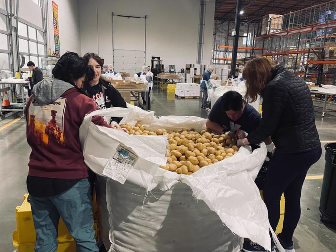 Volunteers sort potatoes at a food bank warehouse.