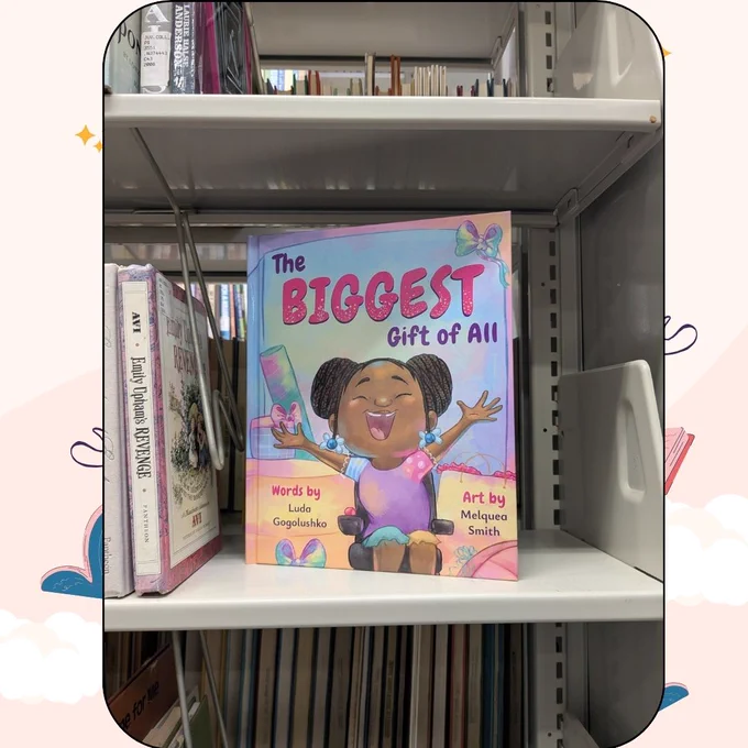 Includes the picture book book, The Biggest Gift of All, standing next to a row of library books.