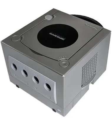 Gray Nintendo GameCube. A grey box with ports on the front, a vented grate on the side and a CD like opening on top with a black circle with GameCube written in white.