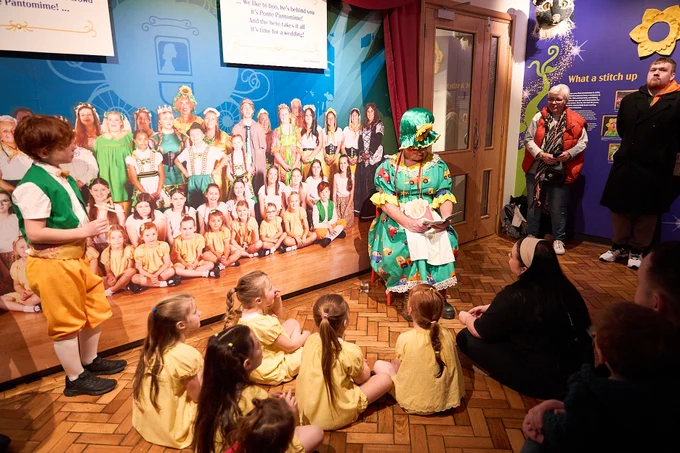 Pantomime character reading to children at the exhibition launch