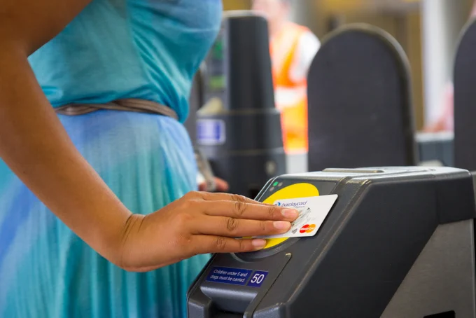 Close up of a woman touching in at a London Underground station using her contactless Mastercard credit card.