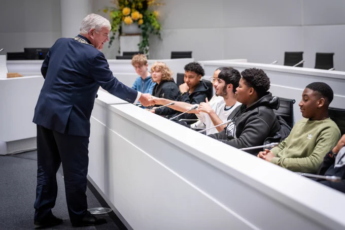 Burgemeester Jan van Zanen groet de leerlingen in de raadzaal van het Haagse stadhuis