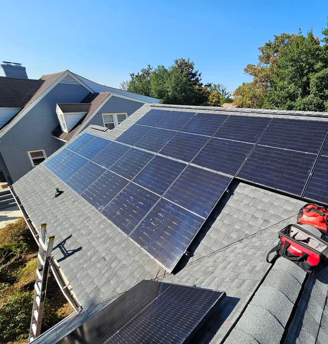 A solar array on a pitched roof, next to two red tool bags.