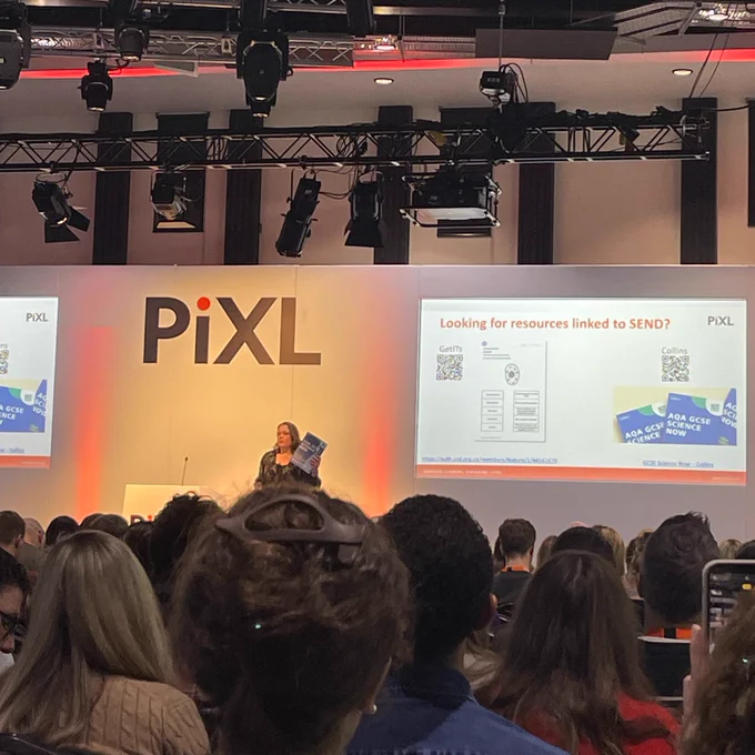 Image shows Karen Collins on stage in front of a packed room of PiXL Science conference delegates holding a copy of AQA GCSE Science Now. 