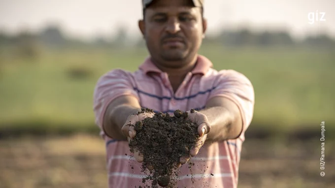 A man stands in a field with soil in his hand