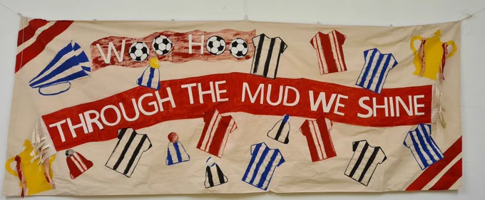 A hand-made banner depicting football jersey designs and the motto 'Through the mud we shine'. 