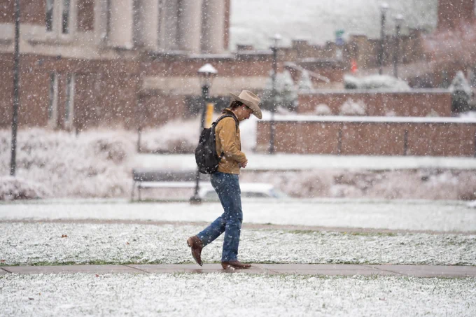 A student walks on campus as it snows. 
