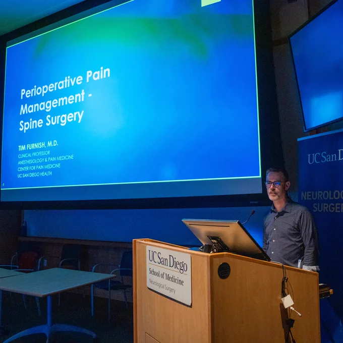 A man standing in front of a large screen.