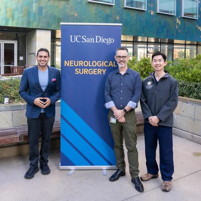 Three people standing around a sign. 