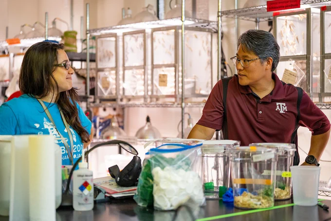 Dr. Techer and Dr. Song converse in the Song Lab. Lab equipment can be seen in the background behind the two. 
