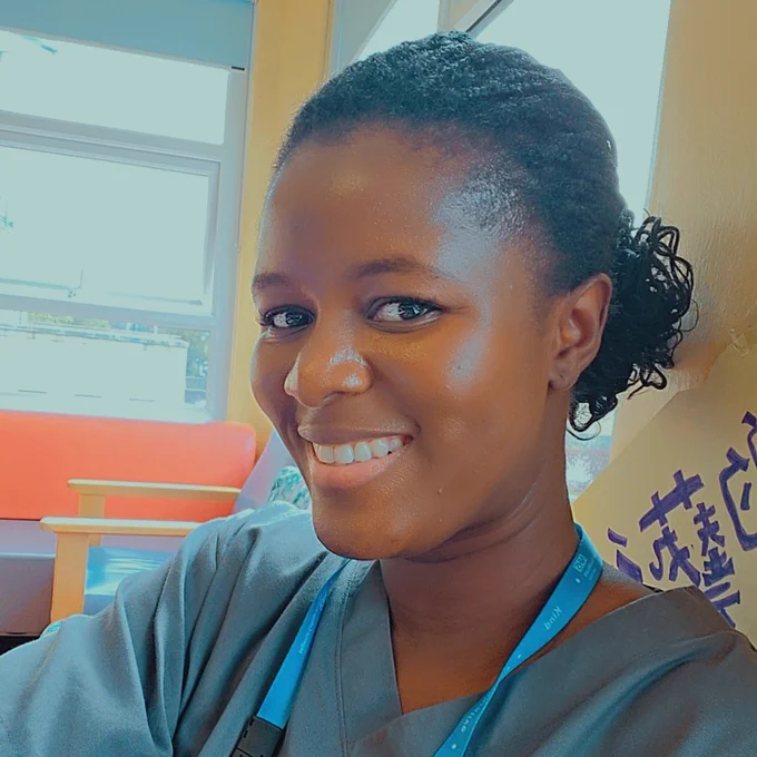 Close up photo of a support worker at Imperial College Healthcare. They are wearing a blue NHS uniform and smiling towards the camera.