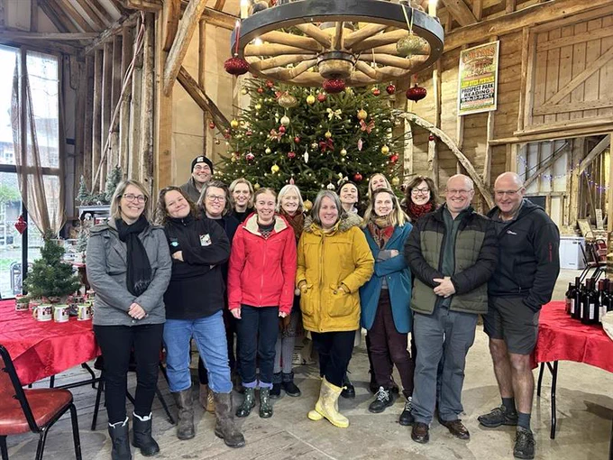 A group of 14 people pose for a photo in front of a large Christmas tree.