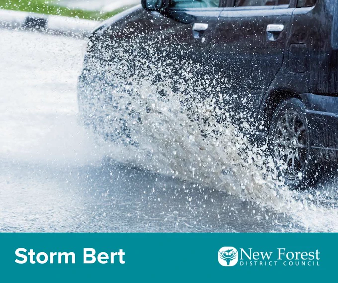 a photo showing a car's tyres close up, driving through surface water on a flooded road
