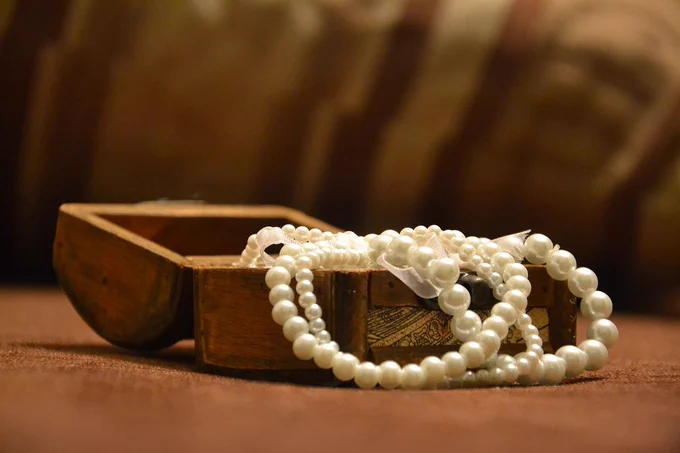 An open wooden box with strings of pearls inside. 