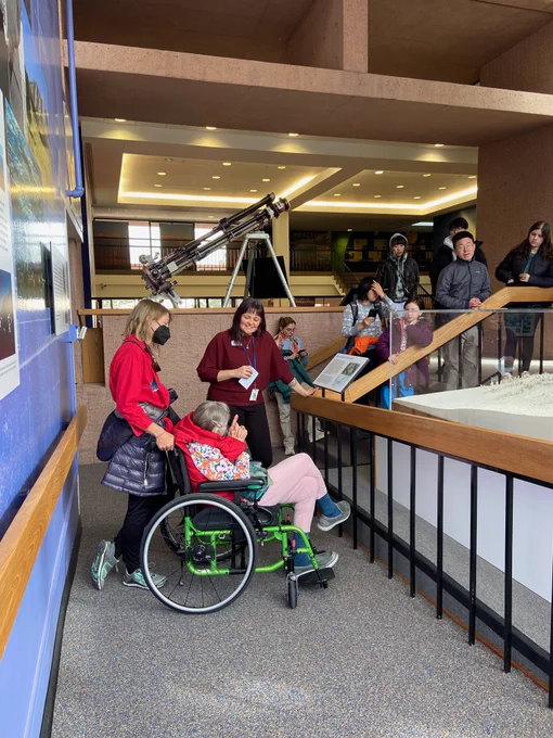 A group of people standing in an atrium of the Mesa Lab surrounding the architectural model of the building