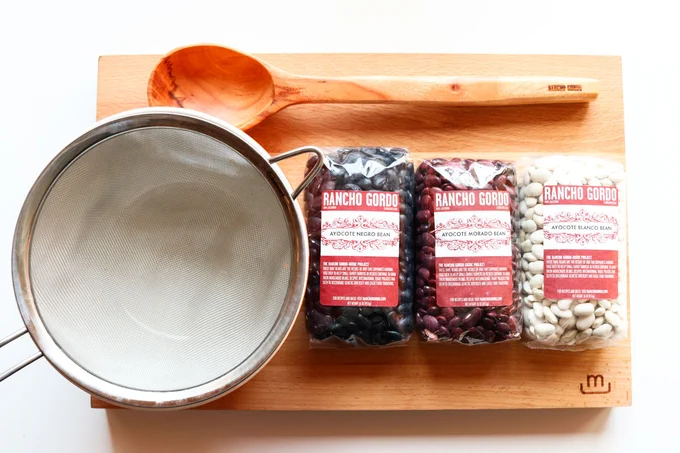 strainer, bowl, spoon, butcher block and Rancho Gordo Ayocote Negro, Ayocote Morado, and Ayocote Blanco beans
