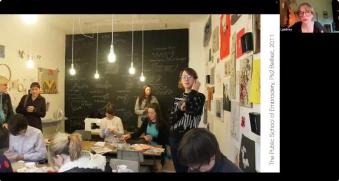 Screenshot from a recording of a talk event with Lyndsey McDougall. It shows one slide from her presentation showing a picture of public embroidery event with many participants. 