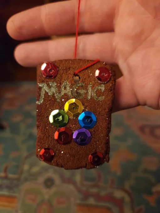 A homemade cinnamon applesauce baked Xmas ornament decorated at the back of a Magic the Gathering card