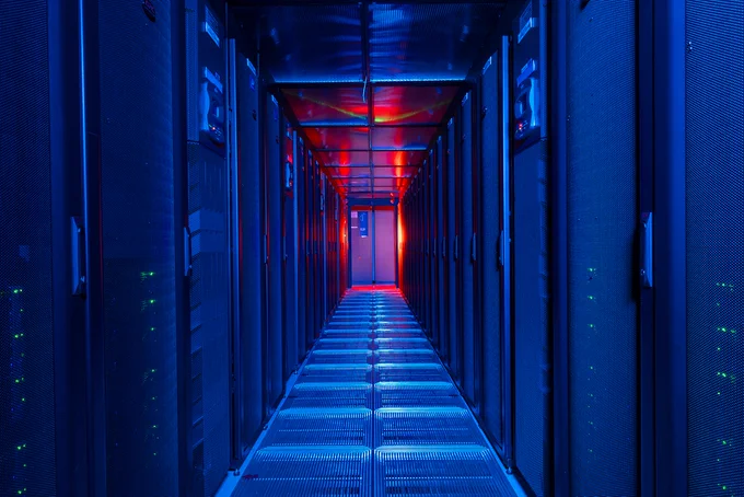 An aisle of supercomputer racks lit up in blue and red