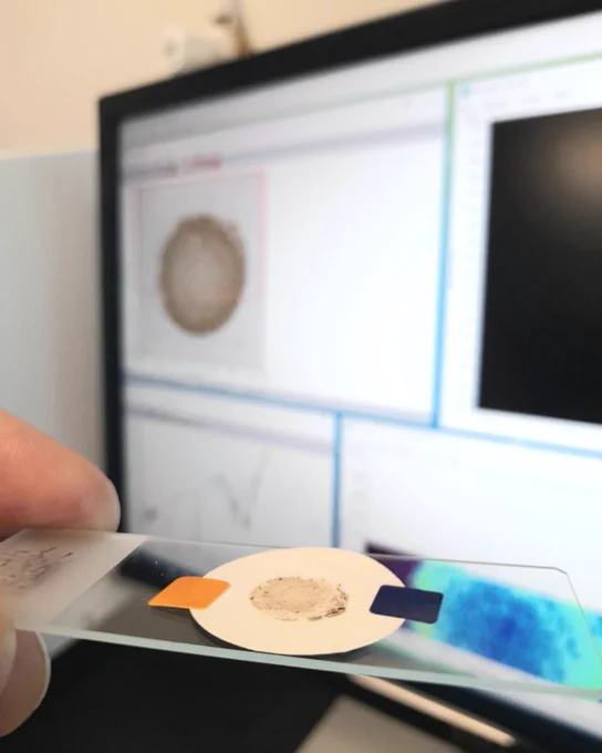 Microplastic sample attached to a slide, with a computer screen in the background