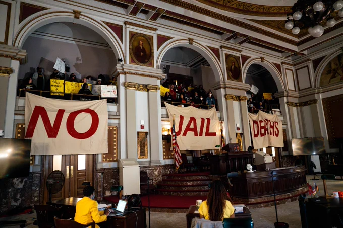 Demonstrators organized by the Freedom Community Center fill the St. Louis Board of Aldermen chambers on Friday, Nov. 22, 2024, at City Hall in downtown St. Louis. The group is calling for public hearings related to the ongoing deaths at the city jail.