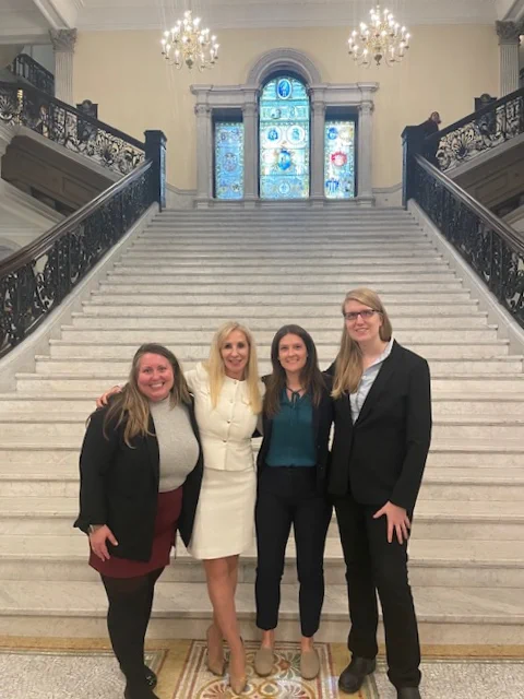 Pictured from left to right on the interior grand staircase steps in the Massachusetts State House: ForHealth Consulting's Whitney Kraemer; Carrie Hill, executive director of the Massachusetts Sheriff’s Association; ForHealth Consulting's Chelsea Thomson; and Emilia Dunham, MassHealth. 