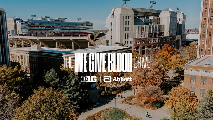 An aerial photo of campus in the fall with text that reads "The We Give Blood Drive" and logos for Abbott and the Big Ten
