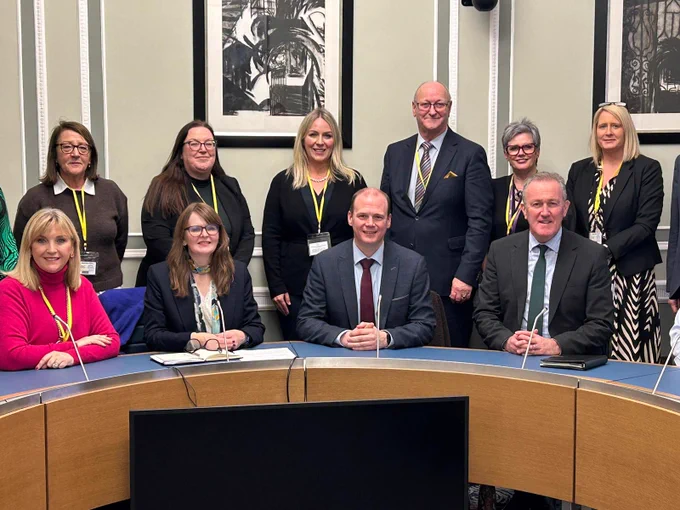 Photo of Celine McStravick sitting with Finance minister, Communities Minister and Economy Minister, with sector reps standing behind.