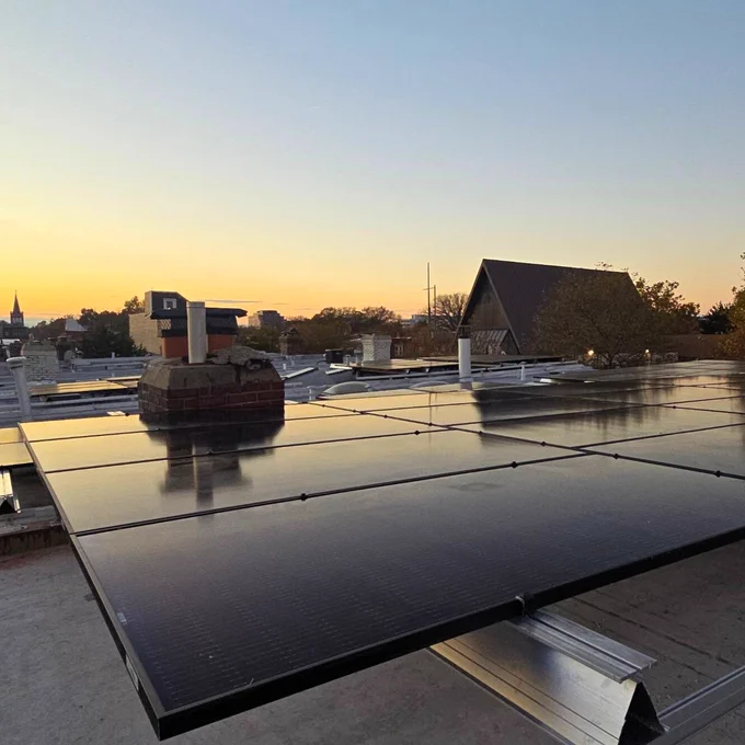 Solar panels at sunset under a blue and orange sky.