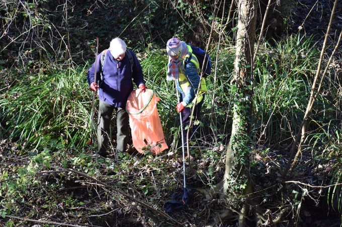 Photo of people litter picking on the riverbank.