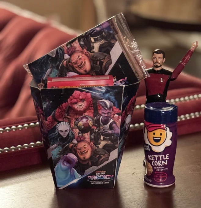 Star Trek Prodigy popcorn bag with popcorn, candy, kettle corn topping, and Little Riker action figure.