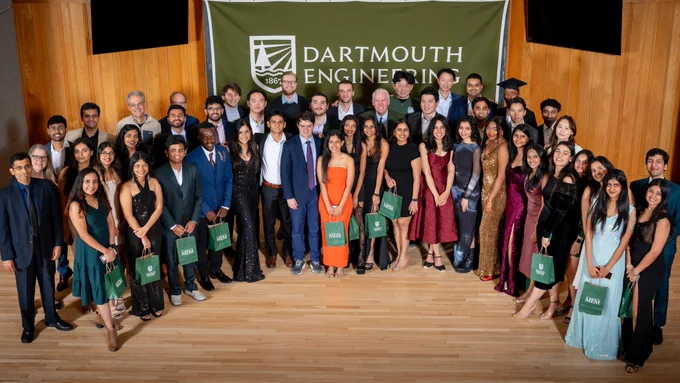 Large group photo of MEM students, faculty members, and program coordinators. There is a green banner that reads "Dartmouth Engineering" in the background. 