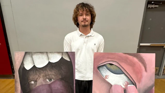 Student stands behind two paintings in Lincoln High Practice gym