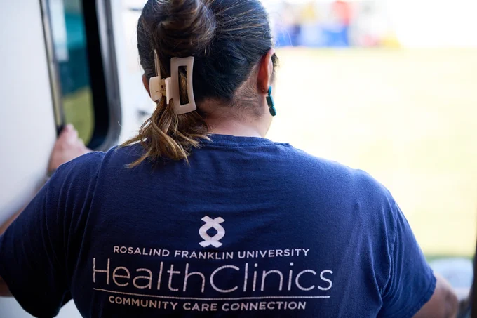 The back of an RFU member's shirt which reads "Rosalind Franklin University HealthClinics Community Care Connection"