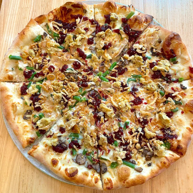 A full shot of the Thanksgiving pizza with creme mushroom base, mozzarella, button mushrooms, green beans, cranberry sauce, turkey, and fried onions.