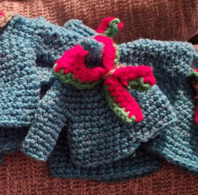 A tiny crocheted jumper including a Green and Red neckerchief on the front.