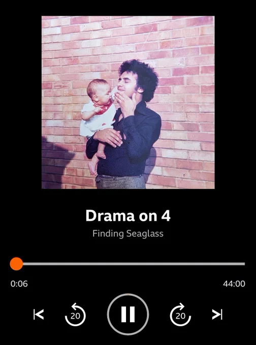 A screenshot of Finding Seaglass playing in the BBC Sounds app. The cover art shows an old photograph of a Black man, Hannah’s father, with a curly Afro wearing a black button-up shirt and holding a baby, Hannah, wearing a white and red dress and reaching her arm towards him.