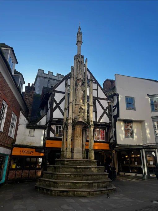 historic stone tall cross in a city centre street 