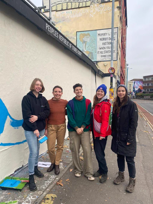 Carla standing with 4 other mural painters 
