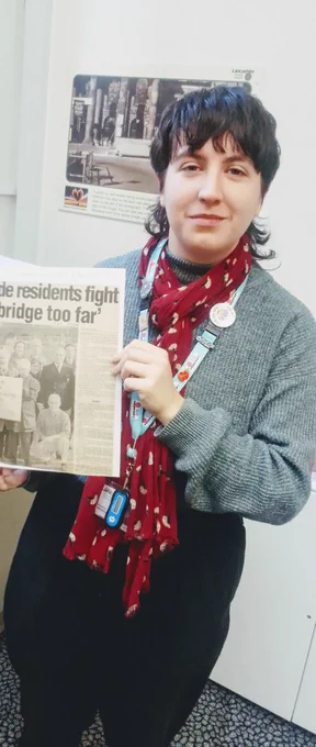 Amelia holding a newspaper article at Lancaster Library.
