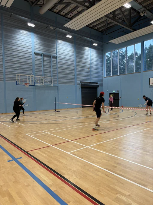 Class of students playing tennis in a sports hall. 