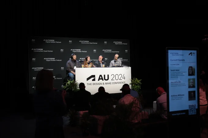 Panel discussion at AU 2024: The Design & Make Conference, with four panelists seated on stage, engaging with an audience in a dimly lit auditorium.