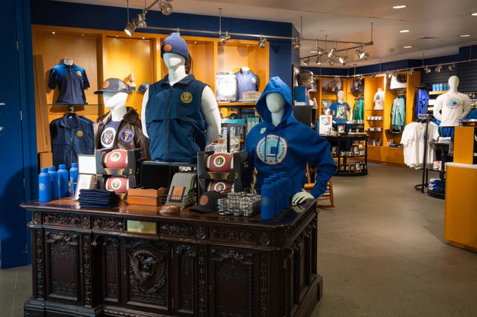 View of the JFK Museum Store, including a replica of the Resolute Desk with footballs, water bottles, and some apparel.