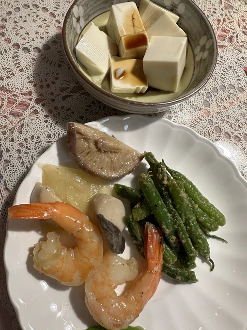 Japanese dish filled with tofu and soy sauce on top. Plate with beans , prawns, shiitake mushrooms onion, ginger…