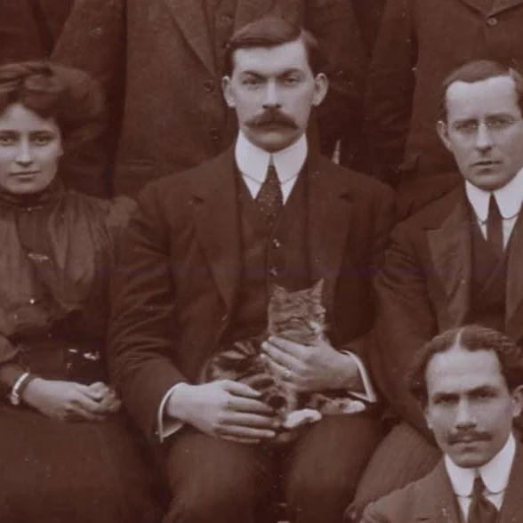 Close up from a LSHTM staff and students photograph from 1911, showing a cat sat in a mans lap.