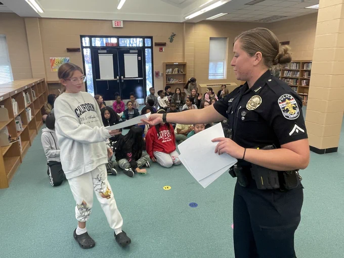 A police officer hands a certificate to a student.
