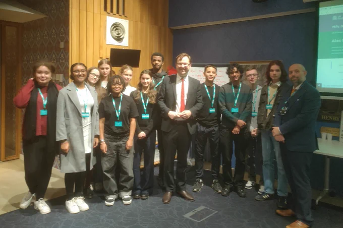Alex smiles with students and staff from Trinity Catholic School during their visit to parliament.  