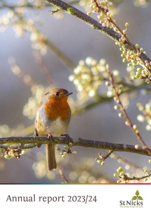 a photograph of a robin sat on a branch. below the photo is the title Annual Report 2023/23 St Nicks