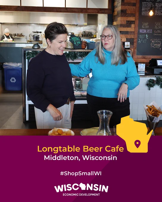 Two individuals smiling and interacting at Longtable Beer Cafe in Middleton, Wisconsin, with the cafe counter and various dishes in the background. Promotional text for #ShopSmallWI by Wisconsin Economic Development is displayed.